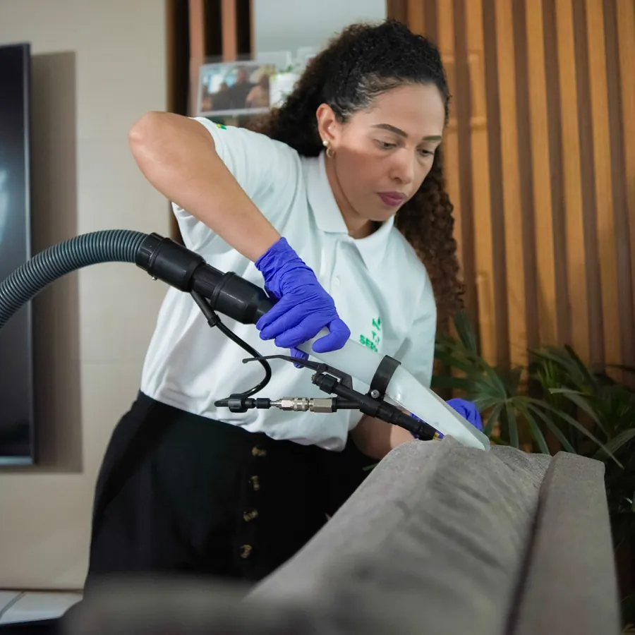 Técnica da T.T Service limpando sofá cinza com a extratora